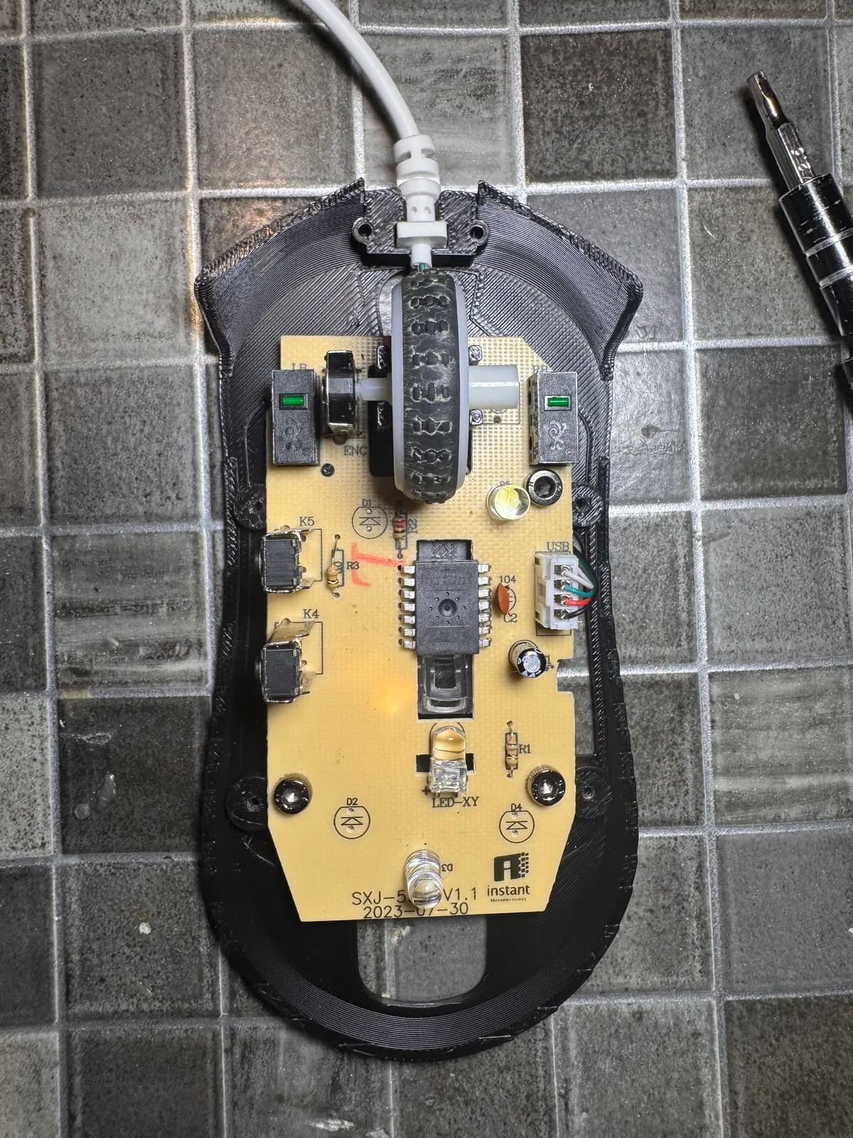 The printed base plate with the mouse PCB screwed into it and the cable routed underneath